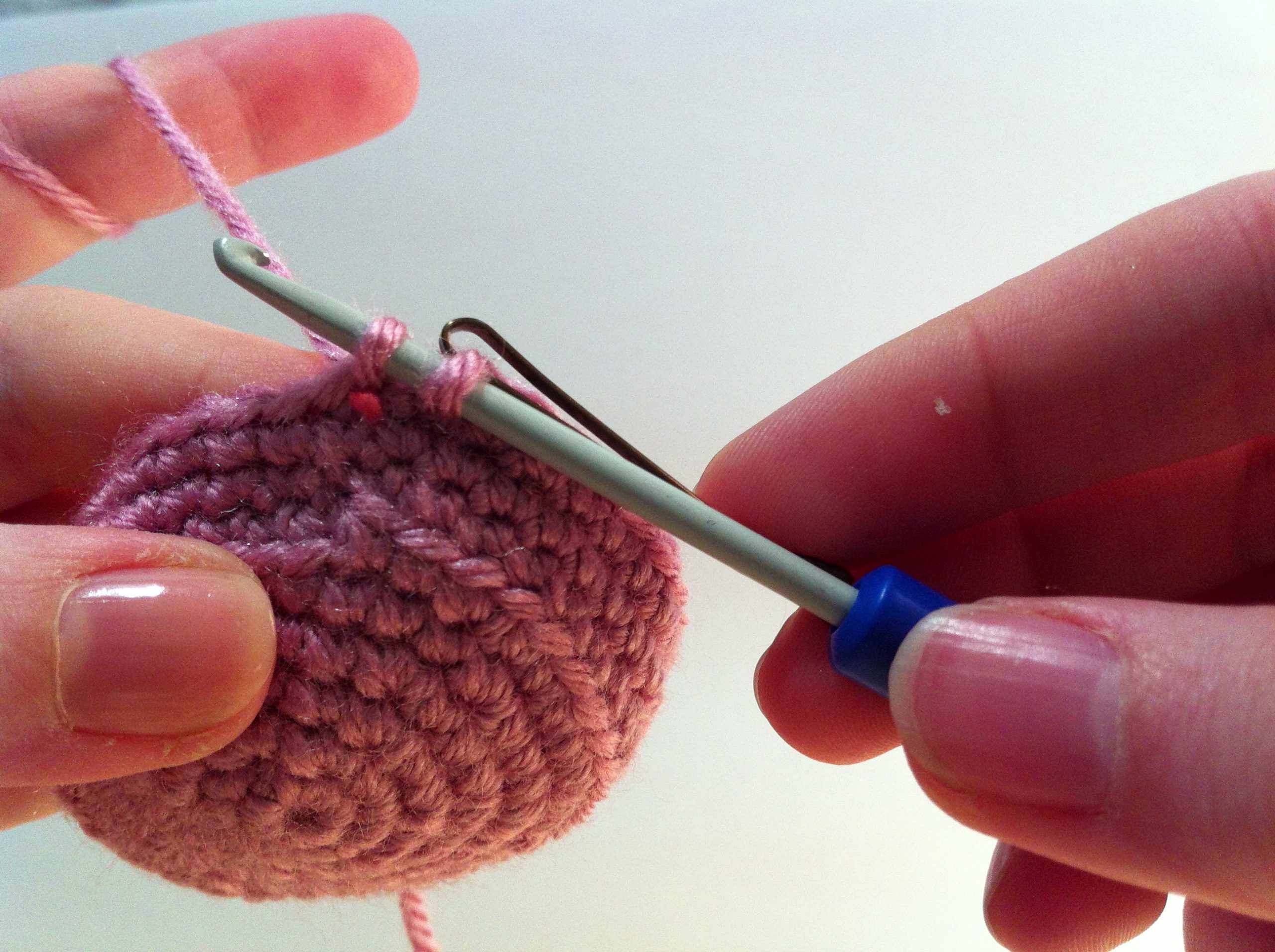 An image of an amigurumi circle and a crochet hook with two loops of yarn drawn up